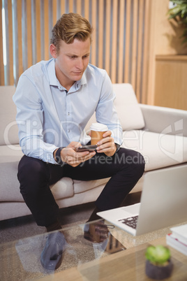 Attentive executive using mobile phone while having coffee