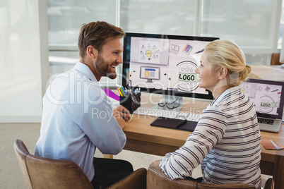Smiling executives interacting at desk