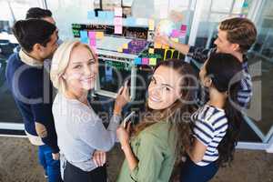 Portrait of business people standing by plan on glass wall