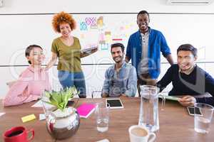 Portrait of business people at desk against whiteboard