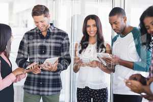 Smiling businesswoman with team using mobile phones and digital tablets