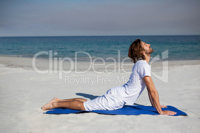 Man performing yoga at beach