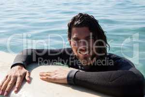 Surfer leaning on surfboard in sea