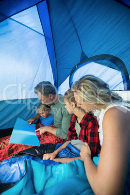 Family reading book in the tent