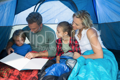 Family reading book in the tent