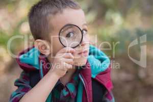 Little boy looking through magnifying glass