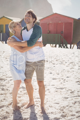 Happy mother embracing her son while standing at beach