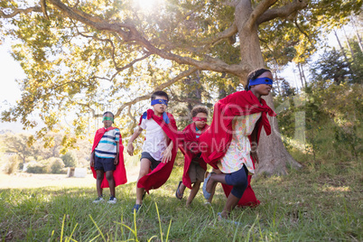Group of friends in superhero costumes runing at campsite