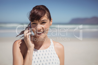 Happy woman talking on mobile phone at beach