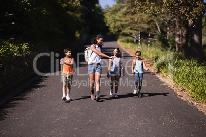 Happy kids and teacher walking on street