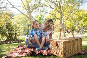 Daughter sitting on mothers lap while having picnic