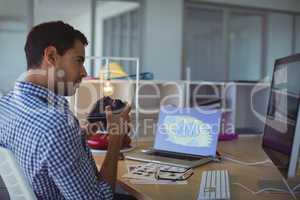 Photographer holding camera while sitting in creative office