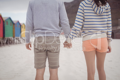 Couple holding hands while standing at beach