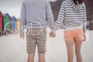 Couple holding hands while standing at beach