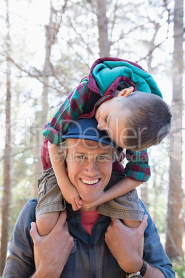 Portrait of happy father carrying son on shoulders
