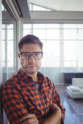 Serious businessman with arms crossed standing in office