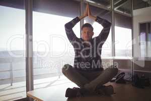 Young businessman meditating on table at office