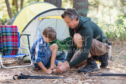 Father helping son to wear sandals by tent