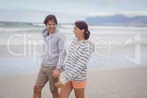 Happy young couple holding hands at beach