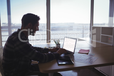 Young businessman using laptop on desk in office