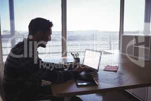 Young businessman using laptop on desk in office