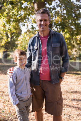 Portrait of happy man and boy standing in forest