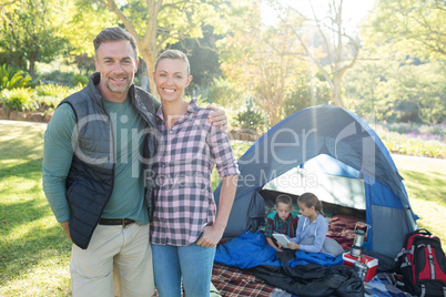 Couple smiling at camera while kids sitting in tent