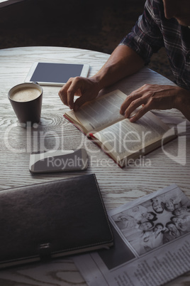 Mid section of businessman reading magazine on table