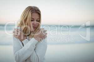 Young woman with eyes closed hugging self at beach