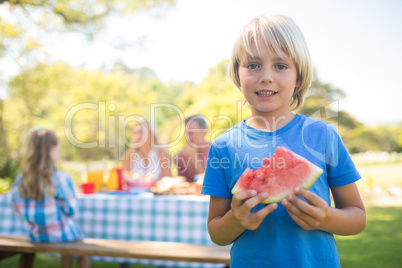 Smiling boy holding watermelon in the park