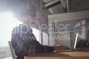 Businessman wearing virtual reality headset while using laptop in office