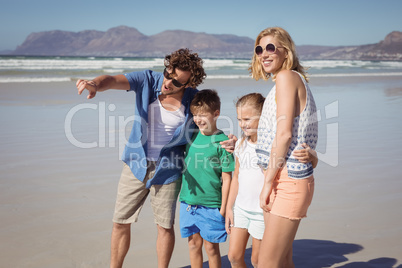 Man pointing away with family standing at beach