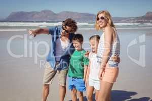 Man pointing away with family standing at beach