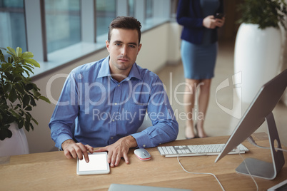 Portrait of executive using digital tablet at desk