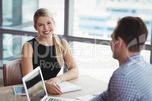 Portrait of smiling executive sitting with her colleague at desk