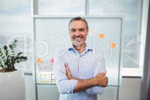 Portrait of smiling executive standing with arms crossed