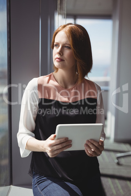 Thoughtful executive holding digital tablet