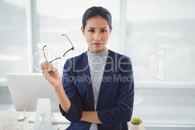 Portrait of confident executive holding spectacles