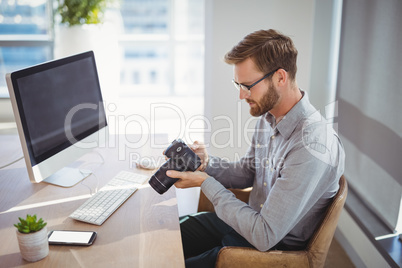 Executive looking at digital camera at desk
