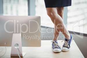 Woman in canvas shoes standing on office table