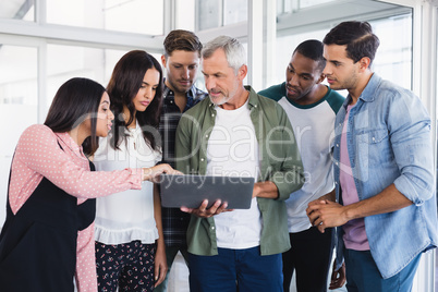 Colleagues looking at laptop held by businessman