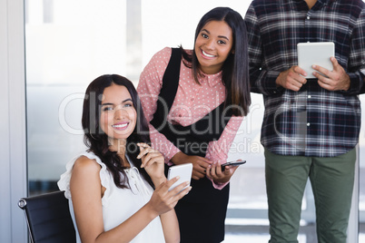 Portrait of smiling business colleagues using mobile phones