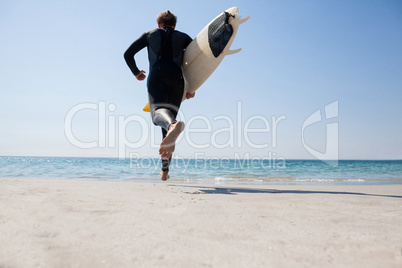 Surfer with surfboard running towards the sea