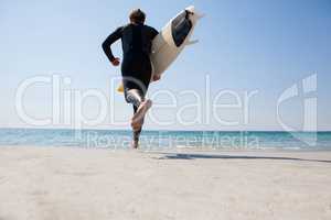 Surfer with surfboard running towards the sea