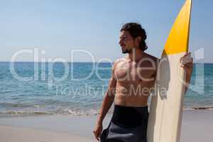 Surfer with surfboard standing at beach coast