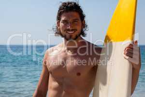 Smiling surfer with surfboard standing at beach coast