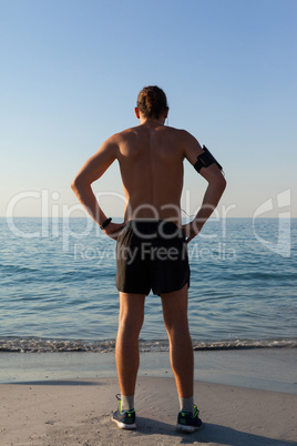 Muscular man looking at sea from beach