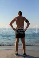 Muscular man looking at sea from beach