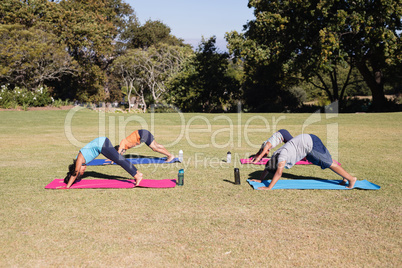 Side view of kids practicing downward facing dog pose