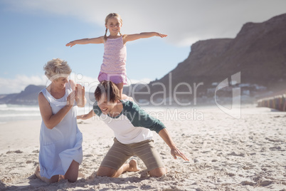 Happy girl kneeling on father back at beach